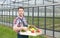 Happy farmer in front of a greenhouse with vegetables