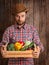 Happy farmer holding wooden box of vegetables