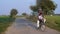 A happy farmer wearing Kurta-Pajama dropping his young son to school on a bicycle - village education