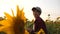 Happy farmer woman working with a tablet in a sunflower field in sunset. An agronomist studies a sunflower crop and