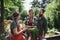 Happy farmers carrying basket with homegrown vegetables outdoors at community farm.