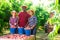 Happy farmers near box of freshly picked peaches in garden