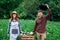 Happy farmers woman and man in hats keep fresh organic vegetables in a wooden box on the background of a vegetable garden. Copy,