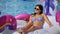 Happy fashion girl in bikini relaxing lying on inflatable mattress sunbathing at swimming pool