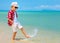 Happy fashionable kid boy walking in surf on tropical beach