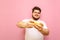 Happy fat gamer playing mobile games on smartphone with smile on face on pink background. Curly overweight kid in white t-shirt