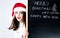 Happy fat Santa girl. A model in a santa hat. XXL a woman celebrating Christmas and a new year. Holds a plaque with the New