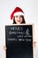 Happy fat Santa girl. A model in a santa hat. XXL a woman celebrating Christmas and a new year. Holds a plaque with the New