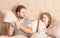 Happy father and daughter having pillow fight in a bed