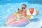 Happy father and daughter with inflatable ring and ball in swimming pool