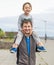 Happy father giving shoulder ride on his shoulders in garden. Happy smiling boy on shoulder dad looking at camera. Father and son