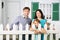 Happy father, mother and daughter stand next to white fence