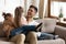 Happy father playing with two daughters, tickling on couch