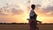 A happy father plays with his son while running through a wheat field. A small boy sits on his father`s shoulders