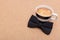 Happy Father`s Day Background. Cup of coffee and black bow tie on brown background flat lay. Fathers day.