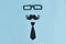 Happy father`s day flat lay. Decorative man mustache, black glasses and bow-tie on a light blue wooden background. top view