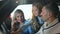 Happy father showing car dashboard to curios cute daughter with blurred mother smiling at background. Side view portrait