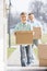 Happy father and son with cardboard boxes entering new home