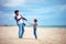 Happy father and son having fun on the beach, playing summer activity games, launching propeller toy in the air
