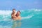 Happy father and son having fun in water waves