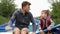 Happy father and son hold paddle and row on boat on lake. Happy father and little child talking and smiling. Young father and litt