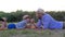 Happy father and son kid play together in arm wrestling lying on plaid outdoors on background of sunset in rural