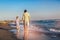 Happy father and son, man & boy child, running and having fun in the sand and waves on the beach