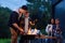 Happy father and son preparing a barbecue on a family vacation on the terrace of their modern house in the evening.