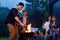 Happy father and son preparing a barbecue on a family vacation on the terrace of their modern house in the evening.