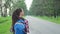 Happy female backpacker admiring nature walking on countryside road