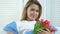 Happy female clinic patient holding red tulips in hands, recovering after labor