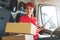 happy female delivery service worker sitting in van and delivering a box