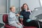 Happy female dentist sitting in dental chair and showing to patient how not to fear working drill, young boy holding the tool and