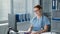 happy female doctor in blue uniform works at the computer with glasses, portrait of girl types on keyboard and then