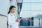 Happy female doctor, smiling and rejoicing, Asian woman uses the phone, during a break near the clinic medical apps, looking at