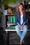 Happy female florist sitting on table in flower shop