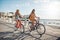 Happy female friends riding bicycles on the seaside road