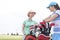 Happy female golfers talking at golf course against clear sky