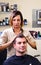 Happy female hairstylist setting client\'s hair