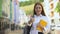 Happy female high-schooler with rucksack and books gesturing thumbs-up, student