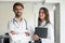 Happy female and male doctors wearing white coats posing indoors