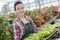 Happy female nursery owner with pot flowers inside greenhouse