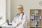 Happy female physician, therapist, general practitioner looking at camera standing in hospital