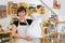 Happy female shopkeeper holding a flour bag in her arms.