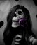 Happy female skeleton wearing a long brown wig and holding a pink rose in her mouth for the Valentine\'s Day