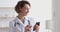 Happy female therapist wearing white coat using smart phone apps