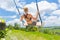 Happy female traveller swinging on wooden swing, enjoying summer vacation among pristine green rice terraces.