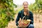 Happy female vintner holding a basket of grapes