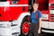 Happy Firewoman Holding Helmet Against Firetruck