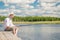 Happy fisherman in a hat on a wooden pier on a beautiful lake wi